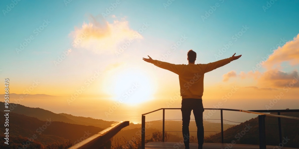 Fototapeta premium A person stands with arms outstretched, embracing the sunset over a tranquil landscape, symbolizing freedom and hope.