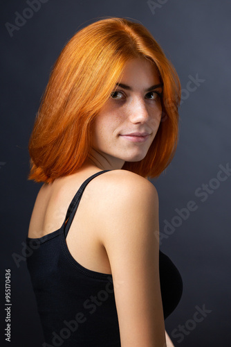 Cute red-haired girl, studio portrait on a black background.