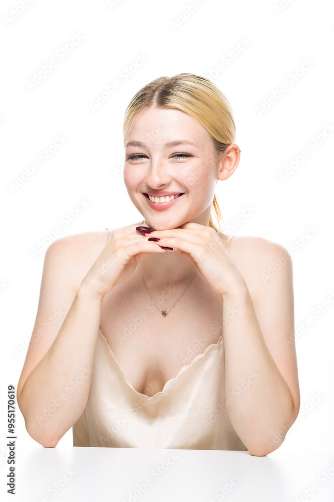 Fototapeta premium A young blonde girl with freckles in a golden top. Beauty portrait of a woman on a white background in the studio.