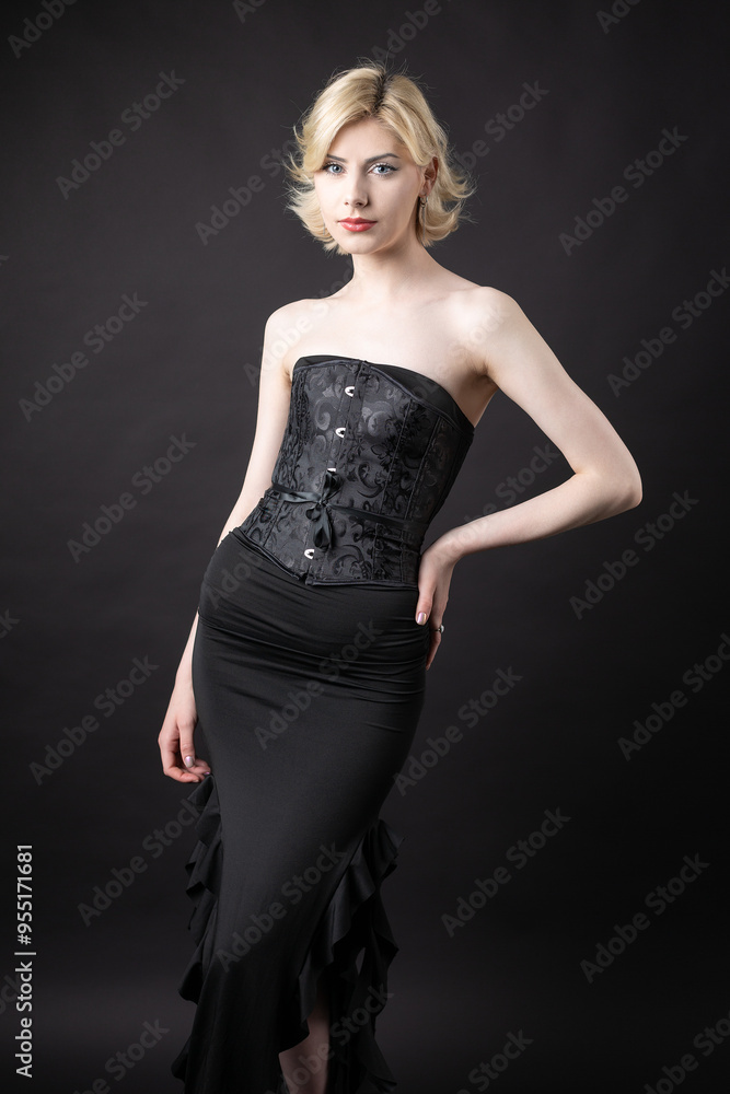 Expressive young blonde under a bob in the studio. In a black corset and dress. Expressive young blonde under a bob in the studio. In a black corset and dress.