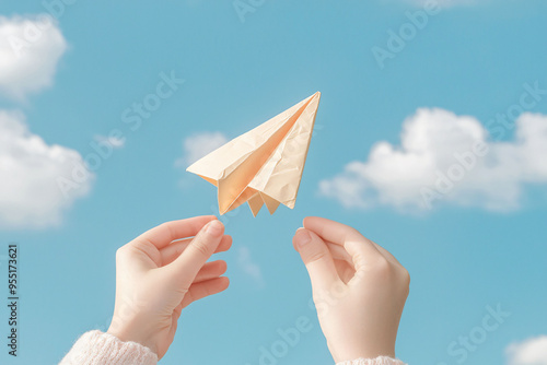 A pair of hands is releasing paper airplane into bright blue sky, evoking sense of freedom and creativity.