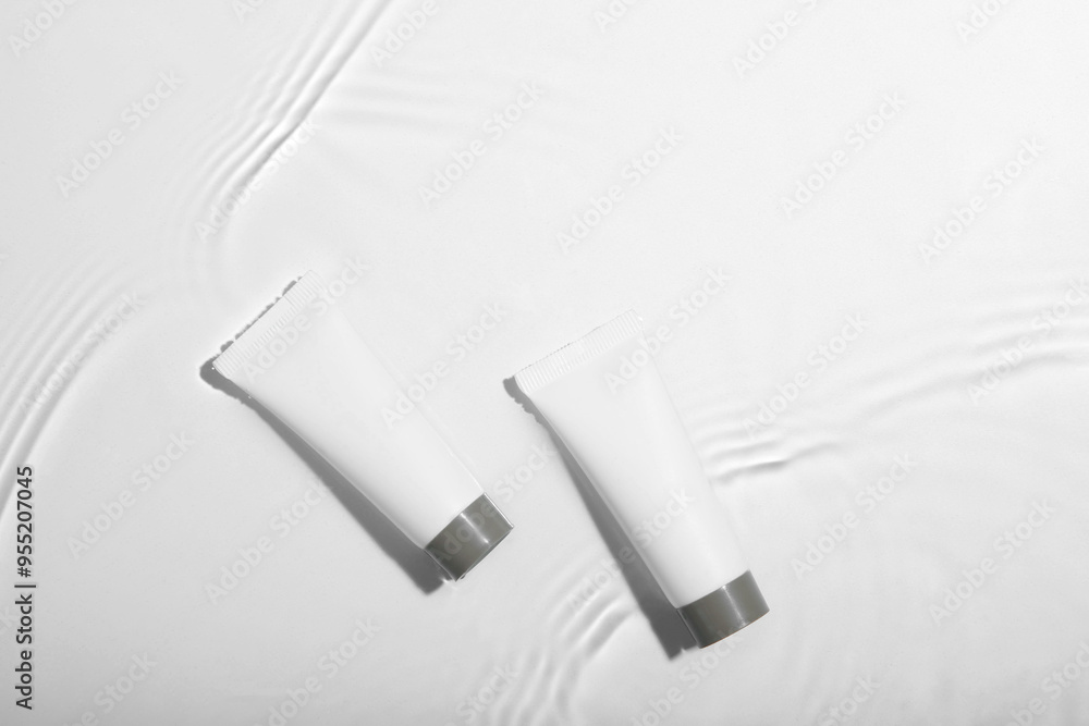 Cosmetic products. Tubes with cream in water on light background, top view Cosmetic products. Tubes with cream in water on light background, top view