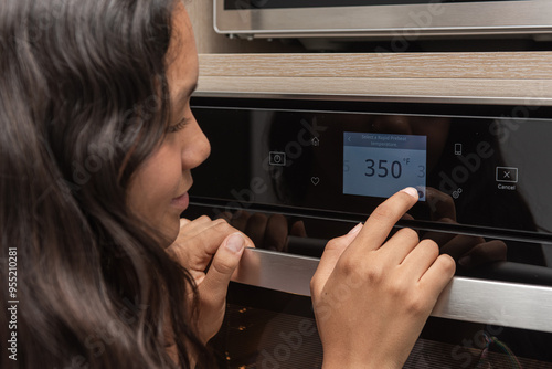 Close up portrait of teenager setting the temperature in the digital oven display.