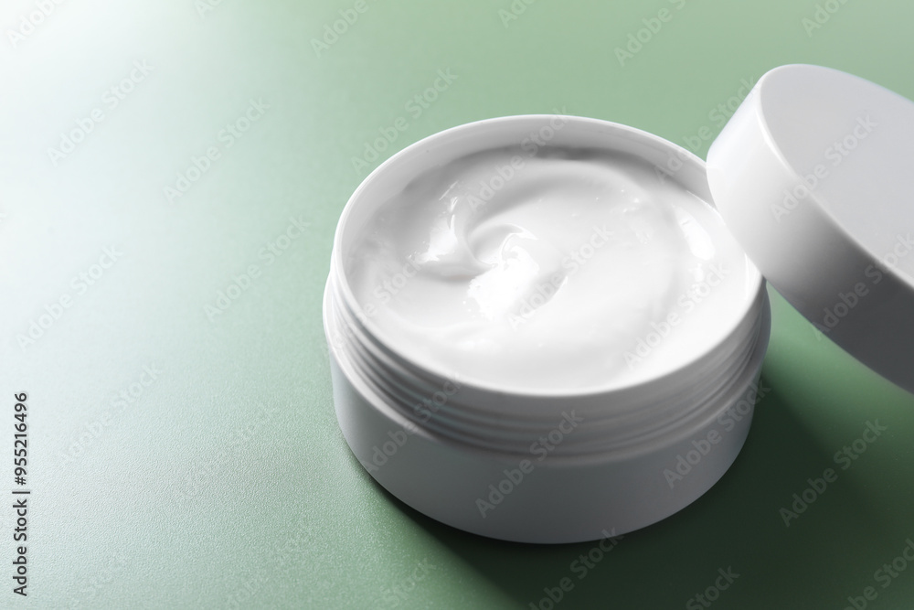 Face cream in jar on green background, closeup. Space for text Face cream in jar on green background, closeup. Space for text