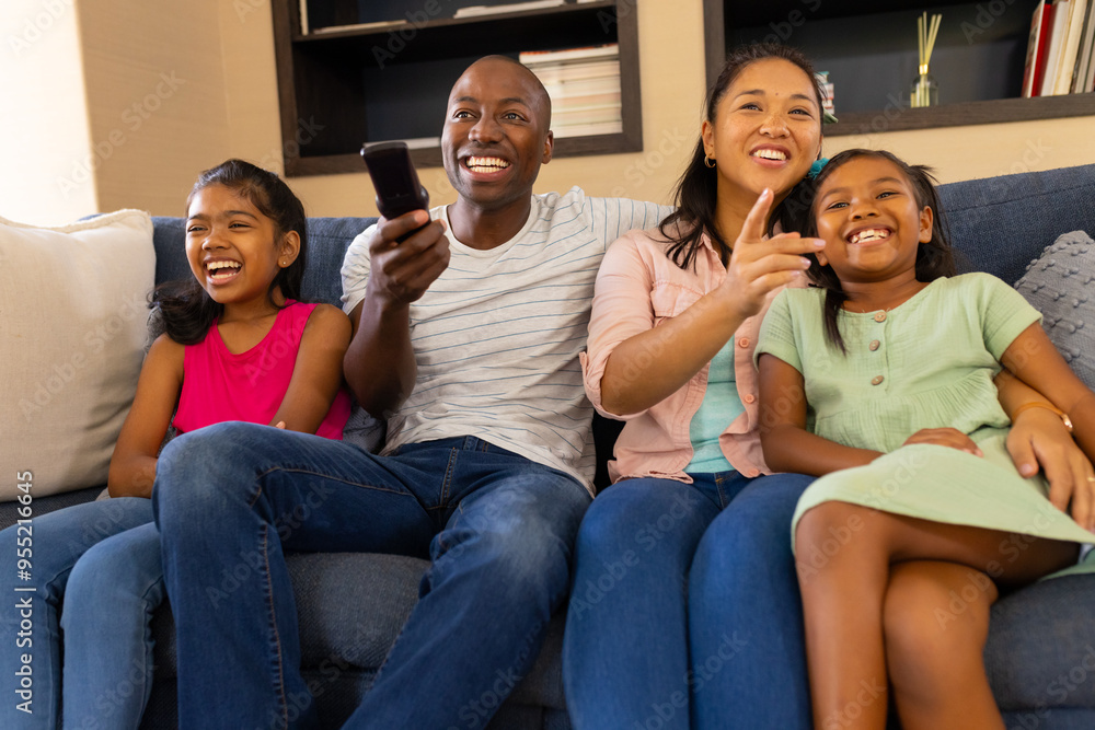 Watching TV, happy family of four sitting on couch and smiling together Watching TV, happy family of four sitting on couch and smiling together
