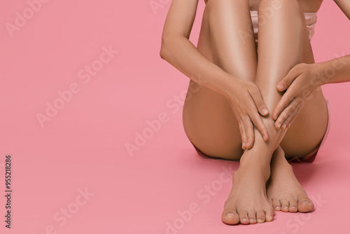 Woman touching her smooth legs on pink background, closeup. Space for text