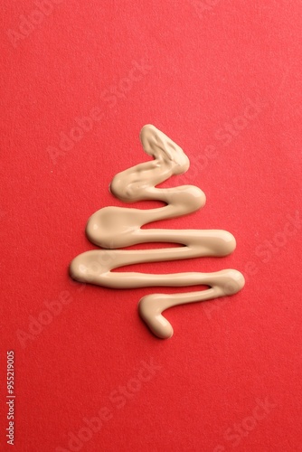 Christmas tree made of skin foundation on red background, top view