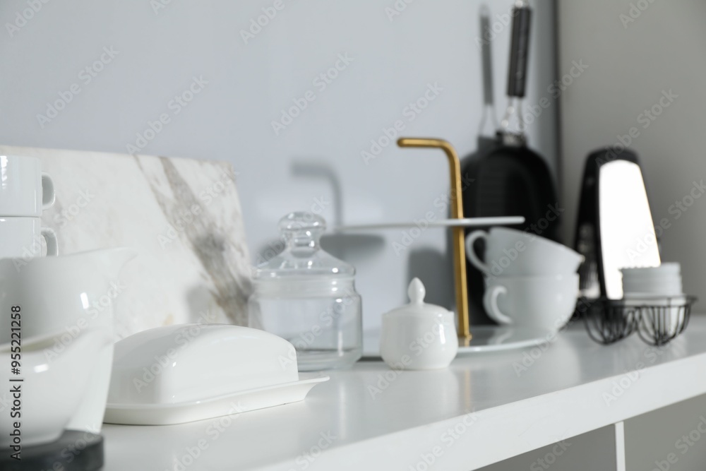 Different kitchenware on white shelf near grey wall indoors, closeup Different kitchenware on white shelf near grey wall indoors, closeup