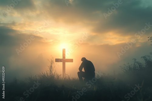 A person kneeling down in front of a cross with sunset over a foggy mountain, religious belief, traditional setting, professional shot