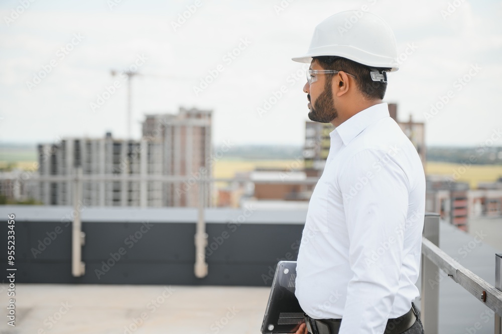 Indian male engineer wearing helmet at construction site. Copy space. Real estate Indian male engineer wearing helmet at construction site. Copy space. Real estate