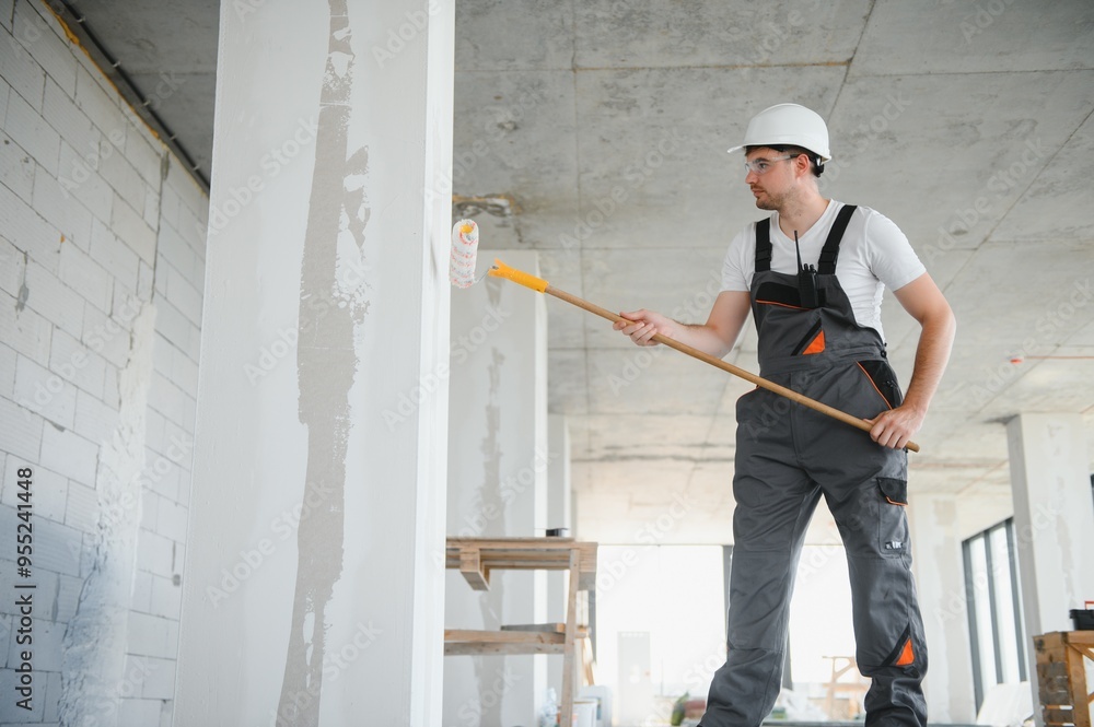 Side view of painter man painting the wall, with paint roller Side view of painter man painting the wall, with paint roller