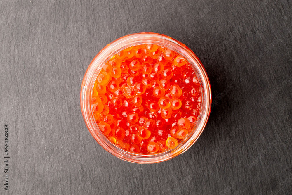Red caviar in a glass jar on a slate stone, macro, top view. Red caviar in a glass jar on a slate stone, macro, top view.