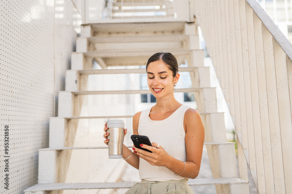 Young happy woman sit on stairs drink coffee and use mobile phone Young happy woman sit on stairs drink coffee and use mobile phone