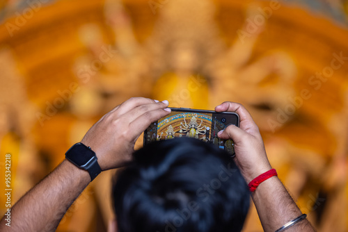 Photography Shubho mahalaya, Hand holding mobile phone and taking photos of Goddess Durga idol at a pandal during navratri