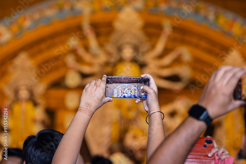 Photography Shubho mahalaya, Hand holding mobile phone and taking photos of Goddess Durga idol at a pandal during navratri