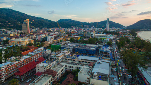 A breathtaking aerial view of a coastal bay at sunset, with golden light reflecting on the calm sea and silhouetted hills in the distance. beautiful reflection of the golden sun at Patong Bay Phuket.