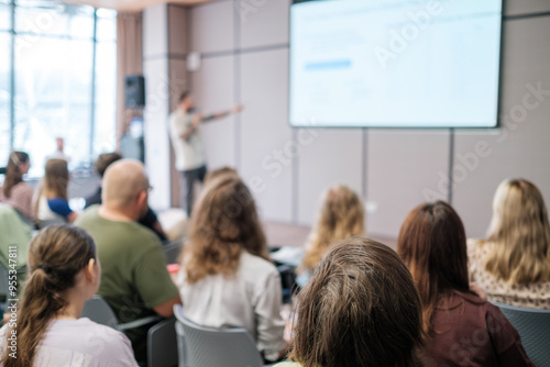 Blurry image of business presentation with audience seated in modern conference room, focusing on learning and collaboration photo