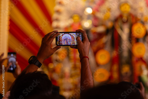 Photography Hand holding mobile phone and taking photos of Goddess Durga idol at a pandal