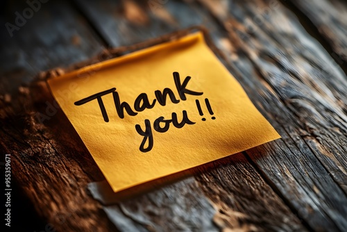 Handwritten thank you note on yellow sticky paper on rustic wooden surface