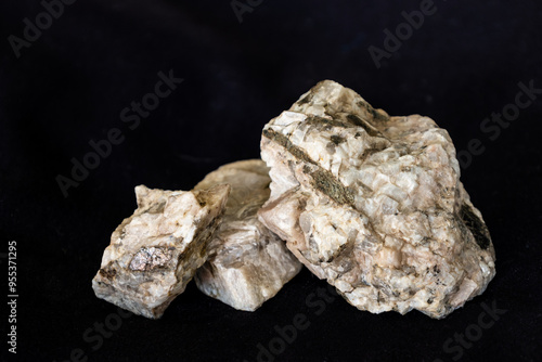 Samples from a granitic pegmatite consisting predominantly of plagioclase feldspar and biotite against a black background.