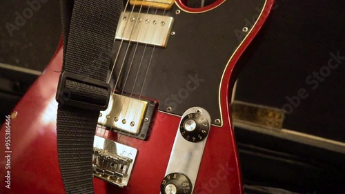 Red electric five string guitar closeup slider shot on black background