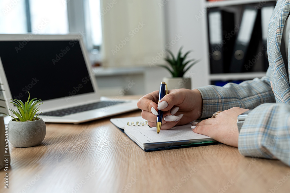 Fototapeta premium female web designer making notes in notepad, use lapton on office workplace