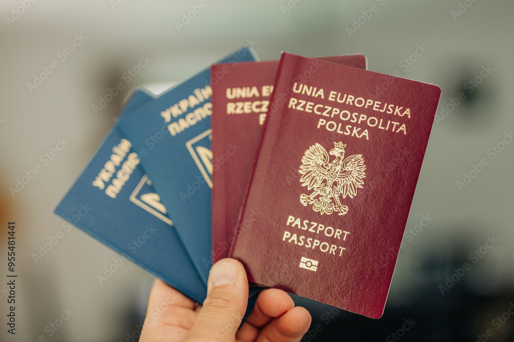 man hand holds both Ukrainian and Polish passports, symbolizing migration and citizenship man hand holds both Ukrainian and Polish passports, symbolizing migration and citizenship
