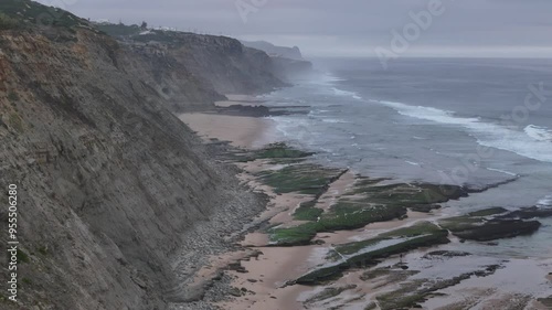 Witness the captivating beauty of Magoito Beach as twilight descends, with waves lapping against the shore and cliffs rising majestically in the background photo