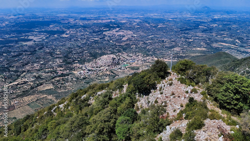 Standing on mountain top overlooking green valley with town and farmland photo