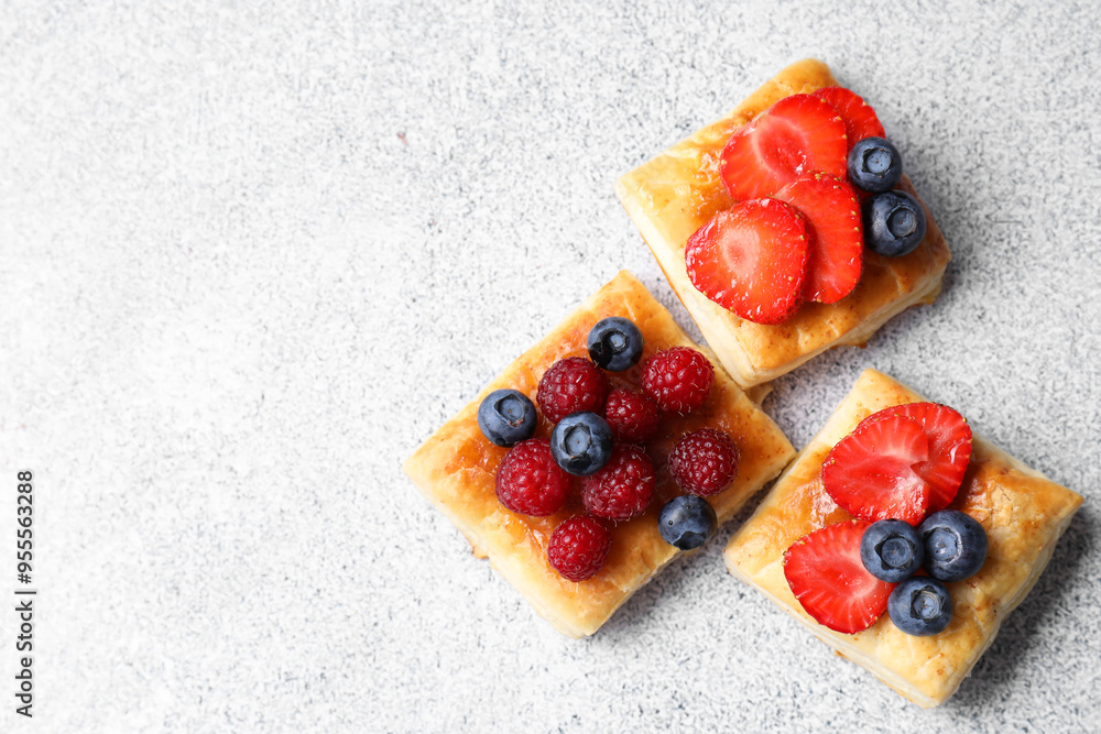 Tasty puff pastries with berries on light grey table, flat lay. Space for text Tasty puff pastries with berries on light grey table, flat lay. Space for text