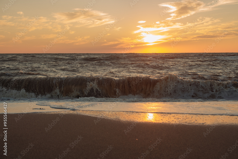 Obraz premium Sunset at sea during a storm. Coast with waves in sea on sunset. Waves in sea during storm and wind. Wave from the sea goes on land to the beach. Splashing Waves, Seaside.
