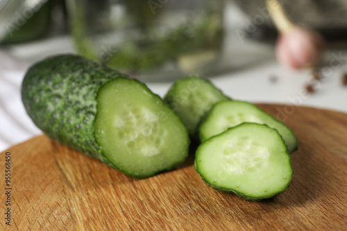 Wooden board with fresh cut cucumber on table, closeup