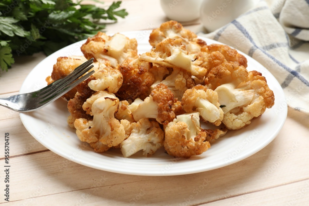 Plate with tasty baked cauliflower on light wooden table, closeup Plate with tasty baked cauliflower on light wooden table, closeup