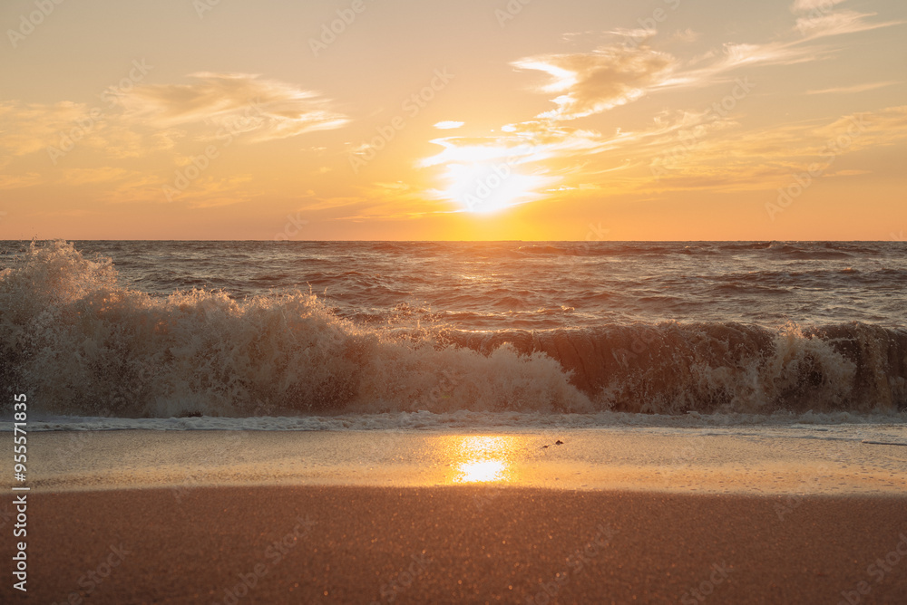 Obraz premium Sunset at sea during a storm. Coast with waves in sea on sunset. Waves in sea during storm and wind. Wave from the sea goes on land to the beach. Splashing Waves, Seaside.
