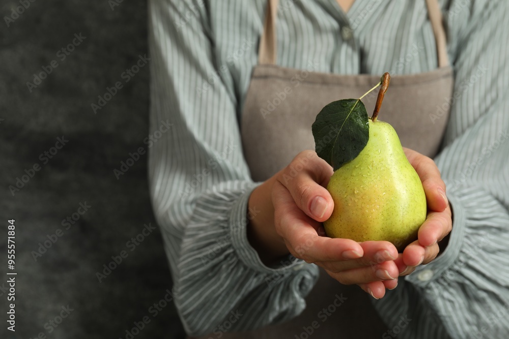 Woman with ripe pear near grey wall, closeup