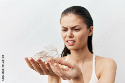 Фотография Hair loss concern, woman with thin hair, frustration expression, holding strands