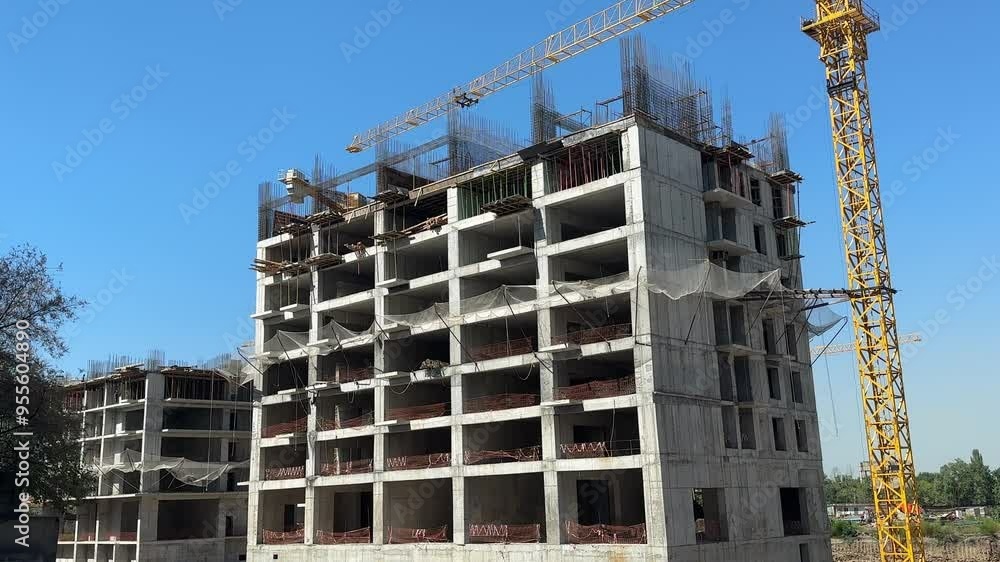 Tower cranes and high concrete residential building under construction. Real estate development concept. Tower cranes and high concrete residential building under construction. Real estate development concept.