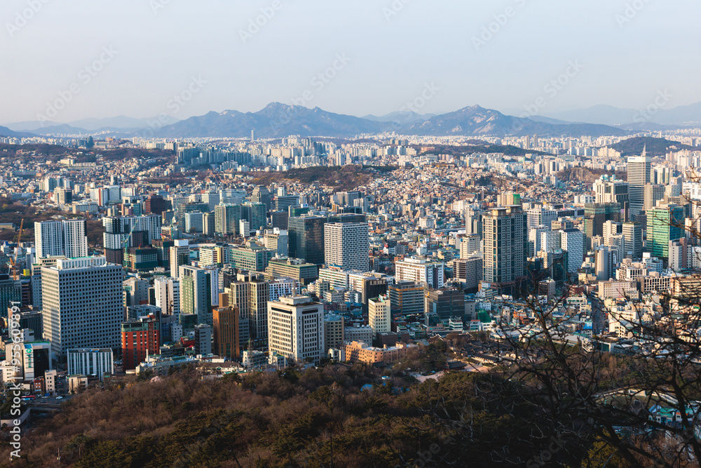 Fototapeta premium Beautiful vibrant aerial sunset view of Seoul, South Korea skyline, with mountains and sprin scenery beyond the city, seen from observation deck of Namsan Park, Gyeonggi-do province, Republic of Korea