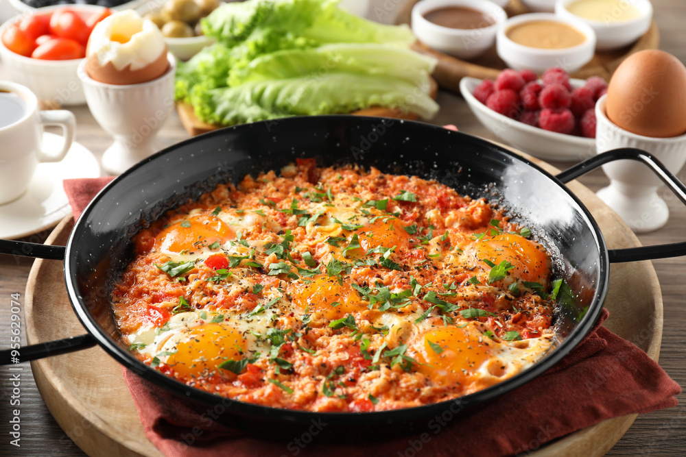 Tasty shakshouka in frying pan served for breakfast on wooden table, closeup Tasty shakshouka in frying pan served for breakfast on wooden table, closeup