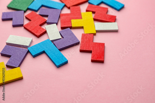 Colorful wooden puzzle pieces on pink background. Space for text