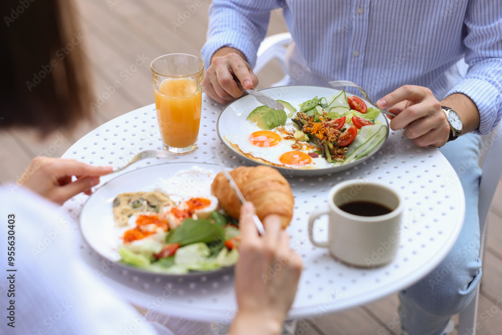Couple having tasty breakfast in outdoor cafe, closeup Couple having tasty breakfast in outdoor cafe, closeup