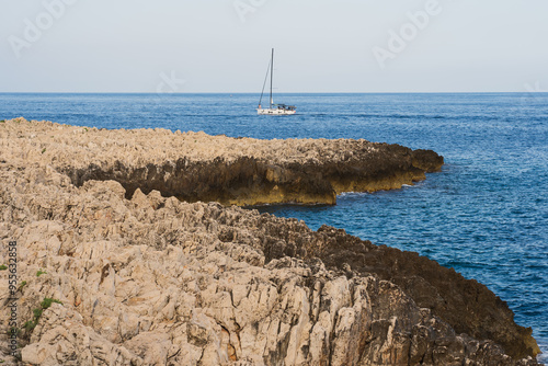 Rocky impassable coast and sailing yacht in the Mediterranean Sea in the south of France near the coast of Saint Jean Cap Ferrat. photo