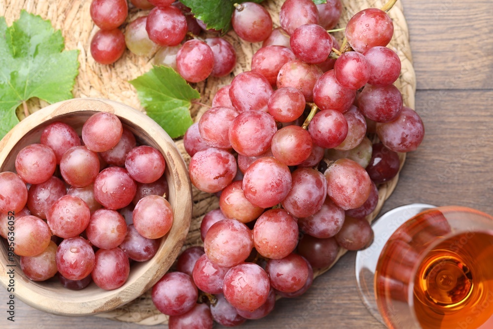 Fresh ripe grapes and glass of wine on wooden table, flat lay Fresh ripe grapes and glass of wine on wooden table, flat lay