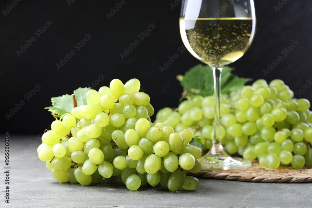 Fresh ripe grapes and glass of wine on grey table Fresh ripe grapes and glass of wine on grey table