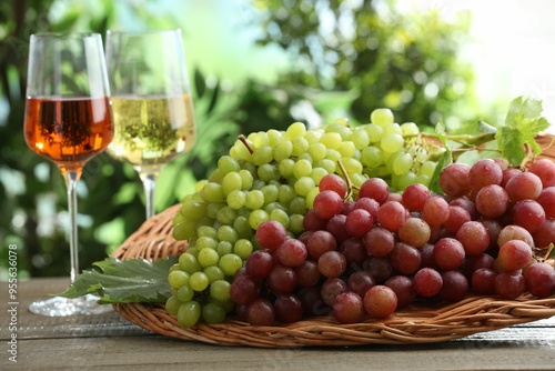 Fresh ripe grapes and glasses of wine on wooden table