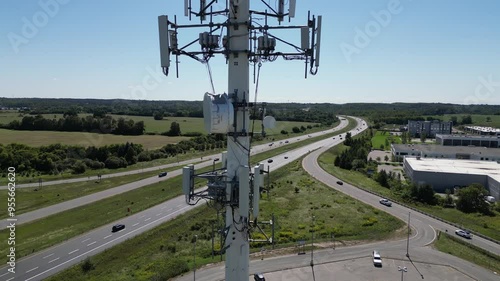 Aerial Drone View of 5G Telecommunications Tower near highway with some traffic on a sunny day