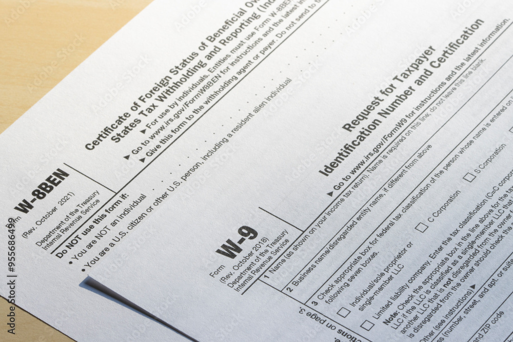 Closeup of Form W-9, Request for Taxpayer Identification Number (TIN) and Certification, and Form W-8 BEN, Certificate of Foreign Status of Beneficial Owner for U.S. Tax Withholding and Reporting. Closeup of Form W-9, Request for Taxpayer Identification Number (TIN) and Certification, and Form W-8 BEN, Certificate of Foreign Status of Beneficial Owner for U.S. Tax Withholding and Reporting.