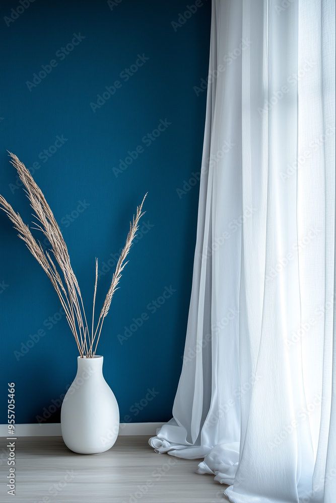Minimalist Vase with Dried Plants. A minimalist home decor with a vase of dried plants on a table against a blue wall. Minimalist Vase with Dried Plants. A minimalist home decor with a vase of dried plants on a table against a blue wall.