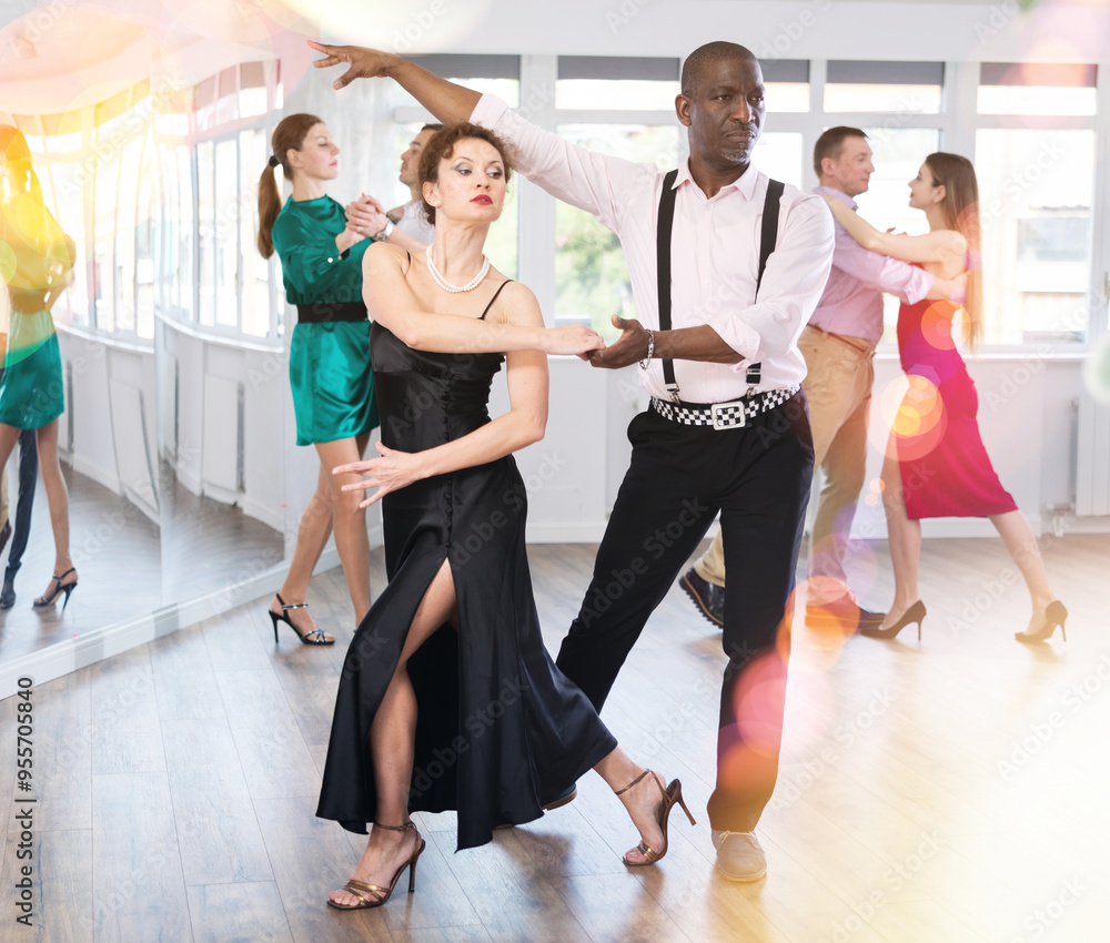 Fototapeta premium Active middle-aged lady training waltz in pair with man in dance-hall during dancing classes