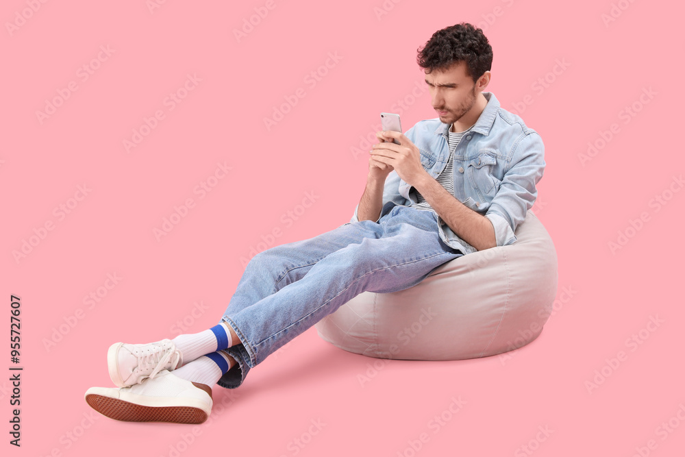 Handsome young man using mobile phone on pink background Handsome young man using mobile phone on pink background